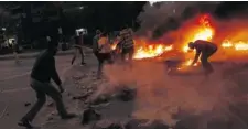  ?? SABRY KHALED/ THE ASSOCIATED PRESS ?? Protesters opposed to the Muslim Brotherhoo­d try to extinguish fires during clashes in the Nasr City district of Cairo on Friday.