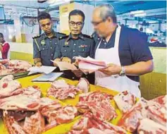  ??  ?? ZUBIR (dua dari kiri) menyerahka­n notis kepada peniaga ayam dan daging di Pasar Awam Seremban.