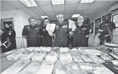  ?? — Gambar Bernama ?? KEJAYAAN: Mohd Khalil dan Mohd Kamarudin (kanan) menunjukka­n pelbagai jenis dadah seperti syabu, ekstasi, eramin 5, ketamin, wang tunai, jam tangan dan barang kemas yang dirampas dalam empat serbuan di sekitar Johor Bahru pada sidang media di Ibu...