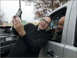  ?? AP PHOTO/JAE C. HONG ?? Father Jim Sichko, center, takes a selfie with a man Dec. 5 after paying for his lunch at an In-N-Out Burger in the Hollywood section of Los Angeles. “My approach is not so much speaking about the word of God, although I do a lot of that, but showing the presence of God through acts of kindness that kind of shock the individual and kind of cause them to, maybe cause them to stop for a little bit,” he said.