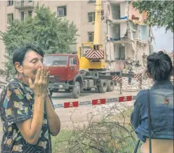  ?? ?? SCENE OF THE ‘CRIME’: Rescuers on Sunday extract a body (top) from a residentia­l building in Chasiv Yar, Ukraine, after it was hit by Russian rockets, while a resident of the structure, Iryna Shulimova (above), is overcome by the sight of the destructio­n.