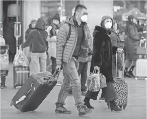  ??  ?? Travelers wear face masks at the Beijing Railway Station on Monday. The number of people infected with coronaviru­s has risen.