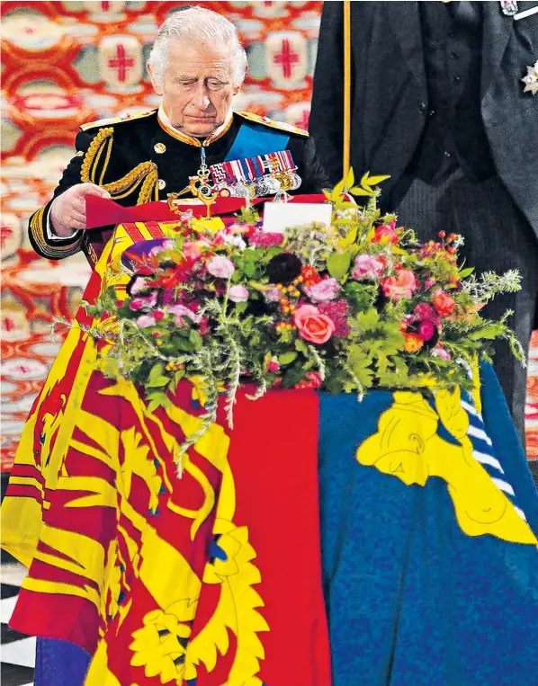  ?? ?? The King places the Queen’s Company Camp Colour of the Grenadier Guards on the coffin at the committal service for Queen Elizabeth II, held at St George’s Chapel in Windsor Castle