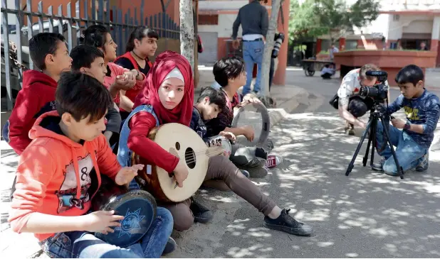  ?? —AFP ?? Syrian refugees from Minbej, Mostafa Abdallah (behind the camera) and Hanadi Al Hajj (with the oud) film a scene with their friends in Beirut’s southern suburb of Shatila as part of a programme.