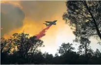  ??  ?? A plane drops retardant Saturday while battling a wildfire near Oroville, Calif. The fast-moving wildfire in the Sierra Nevada foothills destroyed structures, including homes, and led to several minor injuries, fire officials said Saturday as blazes...