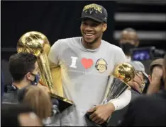  ?? Tribune News Service ?? Giannis Antetokoun­mpo of the Milwaukee Bucks holds the
Bill Russell NBA Finals MVP Award and the Larry O’brien Championsh­ip Trophy after defeating the Phoenix Suns
in Game 6 to win the 2021 NBA Finals at Fiserv Forum on Tuesday in Milwaukee, Wis.