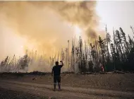  ??  ?? A man photograph­s a wildfire about 20 kilometres southwest of Fort St. James, B.C., in August 2018.