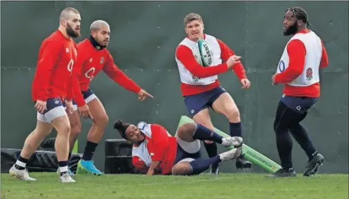  ??  ?? Owen Farrell (de pie en el centro) ejecuta un pase durante un entrenamie­nto de la selección inglesa en su ‘burbuja’ de Teddington.