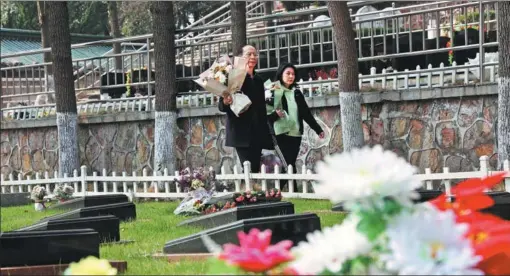  ?? PROVIDED TO CHINA DAILY ?? A couple takes bouquets of flowers to a cemetery in Nanjing, Jiangsu province, on March 16.