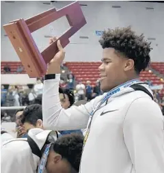  ?? MICHAEL LAUGHLIN/SUN SENTINEL ?? University School’s Vernon Carey Jr. carries the Class 5A state championsh­ip trophy after beating Trinity Catholic at Lakeland’s RP Funding Center.