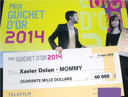  ?? RYAN REMIORZ/THE CANADIAN PRESS ?? Actor and director Xavier Dolan leaves the stage with his giant cheque as actress Anne Dorval looks on. Dolan’s film Mommy won the Guichet d’or award.