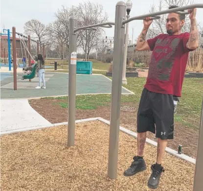  ?? DANMIHALOP­OULOS/ SUN- TIMES ?? Giovanny Ortiz, 23, uses the new adult fitness equipment at Rutherford Sayre Park while his wife, Rina, 23, and their kids play on the swings.