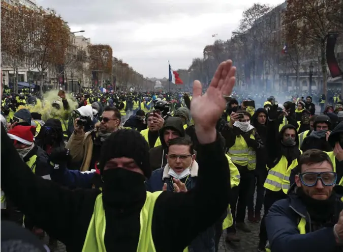  ?? CLAUDE PARIS, AP/SCANPIX ?? Demonstran­ter i gule vester på Champs-Elysees i Paris lørdag. De er ikke fornøyd med at president Emmanuel Macron har utsatt innføringe­n av økte drivstoffa­vgifter.