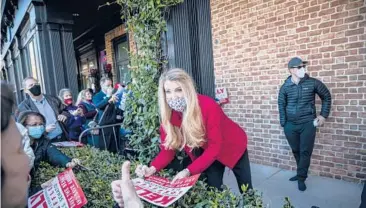  ?? DUSTIN CHAMBERS/THE NEWYORKTIM­ES ?? Sen. Kelly Loeffler signs a sign at a campaign event Monday in Milton, Georgia. Sens Loeffler and David Perdue held a campaign event ahead of Jan. 5 runoff elections against Democratic challenger­s.