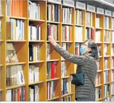  ?? JAVIER ALBIÑANA ?? Una mujer consulta los libros de una estantería de la librería Luces de Málaga.