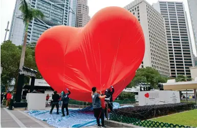  ?? Photos: Dickson Lee ?? Workers deflate the “Chubby Heart” installati­on at Statue Square in Central yesterday afternoon amid strong wind gusts.