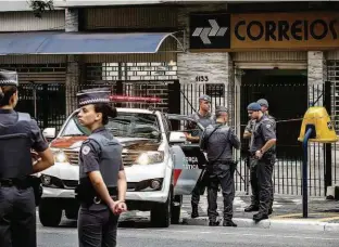  ?? Eduardo Anizelli/Folhapress ?? PMs em frente a agência dos Correios, na avenida Angélica, em Higienópol­is (região central); tiroteio acaba com quatro ladrões presos; um deles foi baleado