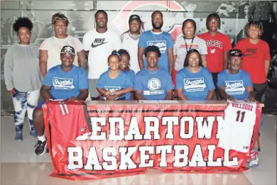  ?? Jeremy Stewart ?? MJ Holiday (seated, center) is joined by his family as he officially signs to play basketball for Shorter University during a special ceremony held Thursday, June 9, at Cedartown High School. The two-sport star scored more than 1,000 points while on the Bulldogs’ basketball team.