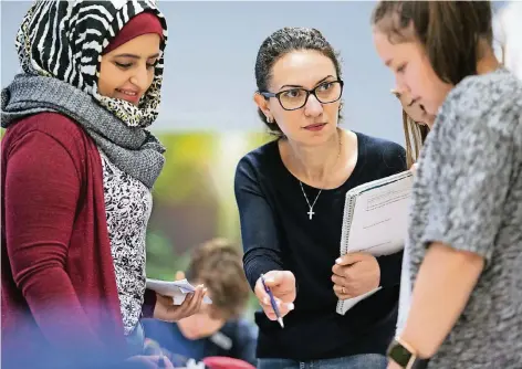  ?? FOTO: DPA ?? Marwa Sulaiman (l.) und Shogine Kamoyan (Mitte) sind aus Syrien und Armenien nach Deutschlan­d geflüchtet. In ihren Heimatländ­ern haben sie als Lehrerinne­n gearbeitet, nun wollen sie zurück in den Beruf. An einer Bielefelde­r Gesamtschu­le hospitiere­n sie...