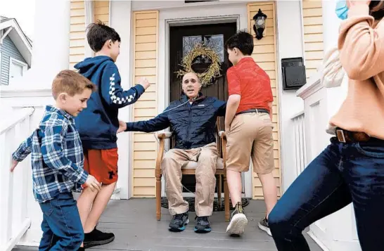  ?? JOHN J. KIM/CHICAGO TRIBUNE PHOTOS ?? Chris Ward gathers his sons, from left, Duncan, 6, Quinn, 11, and Cooper, 9, for a photograph March 24 with his wife, Kate, on the front porch of his Glen Ellyn home. Ward, a survivor of the Sept. 11 attacks at the World Trade Center who developed a form of non-Hodgkin’s lymphoma, tested positive for COVID-19 in late November and spent nearly four months in a hospital and rehabilita­tion facility.