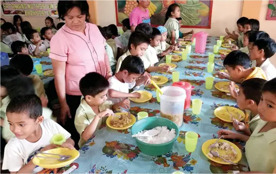  ?? SUNSTAR FOTO/ ARNI ACLAO ?? SPONSORED. Undernouri­shed children enjoy unlimited rice and lomi for lunch at the feeding center in Zapatera Elementary School in Cebu City. School feeding coordinato­r Juliet Julito (left) says 238 students from kindergart­en to Grade 6 are part of the...
