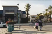  ?? EMILY BERL / THE NEW YORK TIMES ?? People walk down a street in West Covina, Calif., on Feb. 11. Facing a $1.2 million monthly bill from California’s retirement system, West Covina issued bonds through an entity that held the city’s streets as an asset.