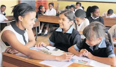  ?? PICTURE: TRACEY ADAMS ?? HELPING HAND: At Bergsig Primary School in Bonteheuwe­l, teaching assistant Leigh-Anne Sylvester assists Rhianna Birch, 9, and Kristin Visagie, 8, in their Grade 4 class.