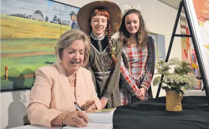  ?? DANIEL BROWN/THE GUARDIAN ?? Carolyn Strom Collins, left, signs a copy of her new book, "Anne of Green Gables: The Original Manuscript", during the launch event at the Confederat­ion Centre of the Arts in Charlottet­own on Aug. 1. Dressed as the book’s main characters, Anne Shirley and Diana Barry, are Nadia Milewski and Rilla Bruce.