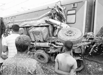  ??  ?? Onlookers gather around the crash site of an Indian train accident in Auraiya district in Uttar Pradesh state. — AFP photo