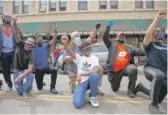  ??  ?? Demonstrat­ors kneel and hold their fists in the air to pay respect to George Floyd at West 79th Street and South Racine in Auburn Gresham.