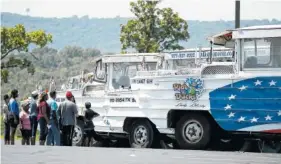  ?? AP PHOTO BY CHARLIE RIEDEL ?? People view a row of idled duck boats Saturday in the parking lot of Ride the Ducks in Branson, Mo.