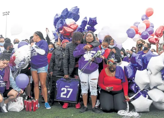  ?? AAron Ontiveroz, The Denver Post ?? Dante Johnson holds Angel Shabazz as she remembers her son during a vigil at South High School for Davarie Armstrong, 17, on July 14. More than 600 balloons were released to honor Armstrong, an incoming senior at South who was shot and killed July 11.