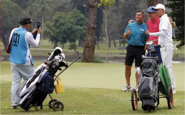  ?? Players have their photos taken by a caddie during a practice round for the 75th PAL Interclub golf tournament championsh­ips at the Del Monte Golf Club in Manolo Fortich, Bukidnon on Tuesday. ??