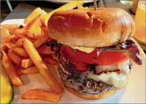  ?? ?? The eponymous burger at the new Albany War Room Tavern is topped with pork belly,
cheese, tomato, greens
and roasted-garlic
aioli.