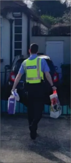  ??  ?? Garda Adam Nolan delivering supplies to a cocooned householde­r in Kilmacanog­ue, Co. Wicklow.