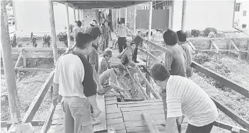  ??  ?? Parents and teachers repairing the plank walk.