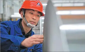  ?? XINHUA ?? A worker inspects an aluminum foil product at a plant in Longxi county, Gansu province.