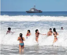  ?? Foto: Herbert Knosowski, dpa ?? Sicherheit geht vor: Während diese Kinder an der Copacabana toben, patrouilli­ert in Sichtweite ein Schiff der brasiliani­schen Marine.