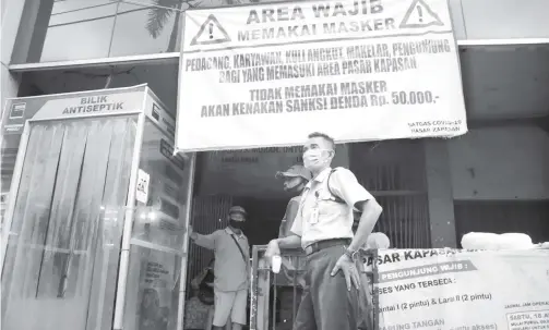  ?? FRIZAL/JAWA POS ?? DISIPLIN: Petugas keamanan sedang berjaga di depan Pasar Kapasan. Satgas percepatan penanganan Covid-19 akan menggelar razia besar-besaran protokol kesehatan di pasar.