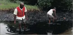  ?? PICTURE: AP ?? In this June 20, 2010 file photo, men walk in an oil slick covering a creek near Bodo in the oil-rich Niger Delta region of Nigeria.