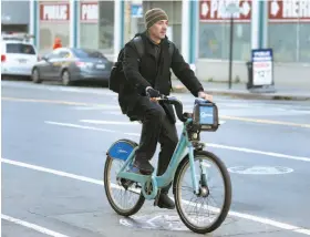  ?? Paul Chinn / The Chronicle ?? A commuter rides a Bay Area Bike Share bicycle on Townsend Street near the Caltrain Terminal in San Francisco.