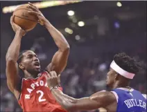  ?? The Canadian Press ?? Toronto Raptors forward Kawhi Leonard (2) shoots over Philadelph­ia 76ers guard Jimmy Butler during first-half NBA action in Toronto on Wednesday. The Raptors won 113-102.