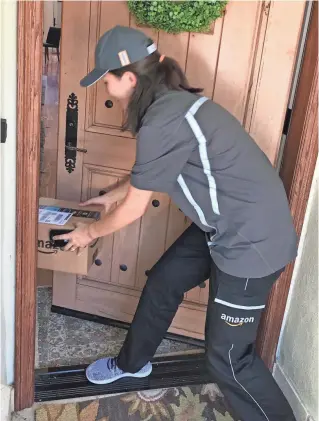  ?? ELIZABETH WEISE/USA TODAY ?? An Amazon Logistics delivery person places a package inside a customer’s front door after having the smart lock on the door opened by the Amazon Key system.