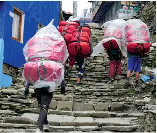  ??  ?? Above left: Our porters climb through Ghorepani Village. Above right: Our cooks also carried their kitchen!