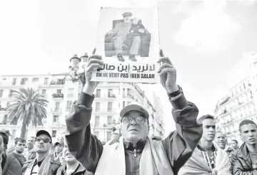  ?? — AFP photo ?? An Algerian protester raises a placard as he takes part in a demonstrat­ion in the capital Algiers. The placard reads in Arabic and French: “We do not want Bensalah” .