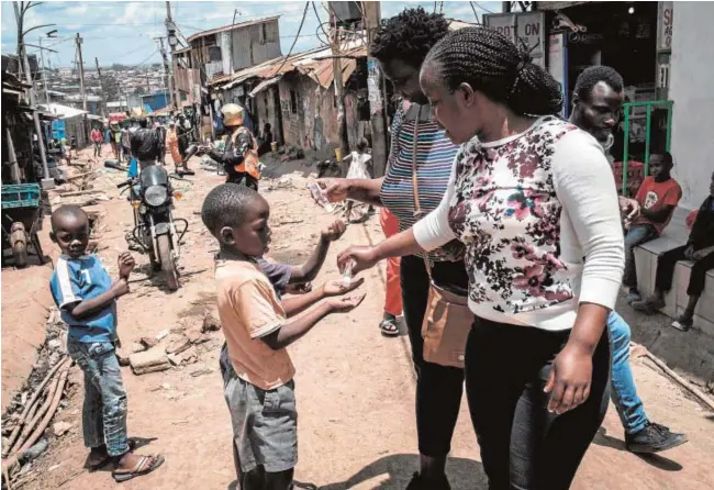  ?? // AFP ?? Un grupo de voluntaria­s de una ONG ofrecen gel hidroalcoh­ólico a los niños en Kibera, un ‘slum’ de Nairobi