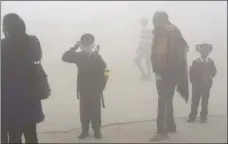  ??  ?? In this Thursday photo, an Indian boy uses a handkerchi­ef to protect his face as school children and parents await transport surrounded by morning smog on the outskirts of New Delhi, India. AP PHOTO/R S IYER