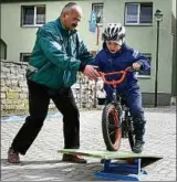  ??  ?? Frank Reinhardt passt im Fahrradpar­cours auf, dass Pascal () sicher über die Wippe fährt.