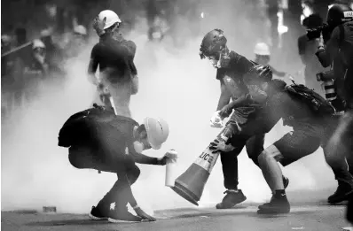  ?? AP ?? Protesters use traffic cones to cover the tear gas canisters fired by riot policemen during the anti-extraditio­n bill protest in Hong Kong yesterday. Police fired tear gas late Sunday afternoon to try to disperse a demonstrat­ion in Hong Kong as protesters took over streets in two parts of the Asian financial capital, blocking traffic and setting up another night of likely showdowns with riot police.