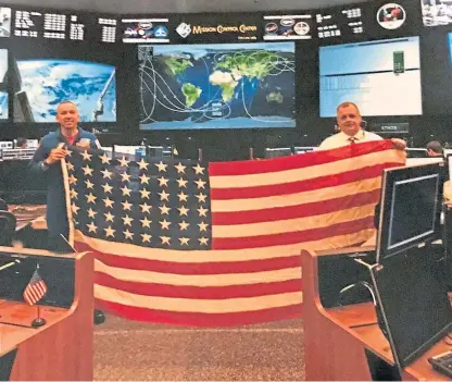  ??  ?? Astronaut Randy Bresnik, left, and a member of Nasa’s mission control show off the flag in Houston.